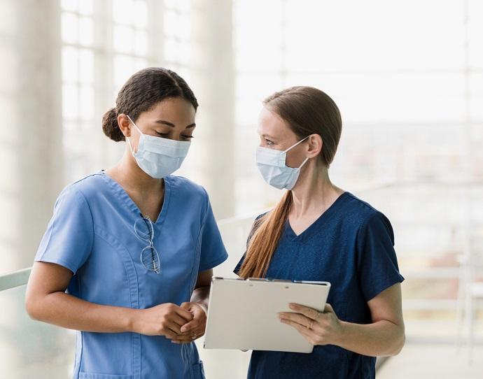 Two nurses in masks looking at a chart