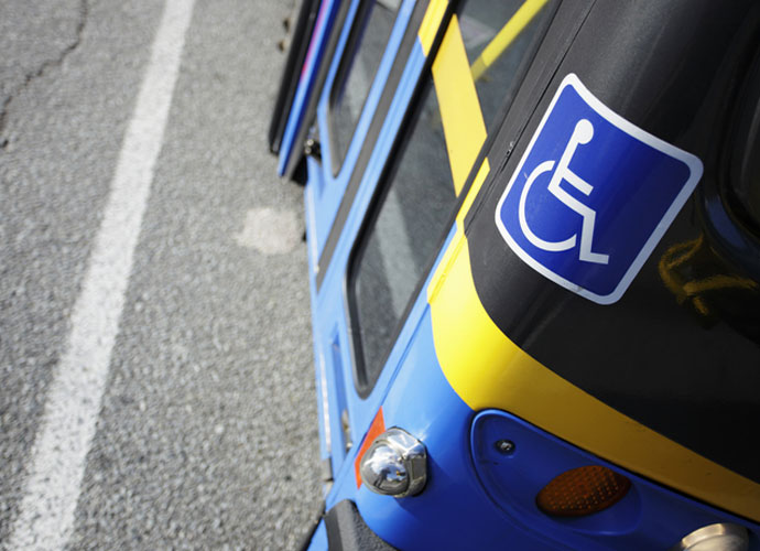 An image of a public bus entrance on the street with a handicap sign next to the door entrance.